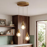 Brushed brass three-light pendant with glass shades hanging in a kitchen