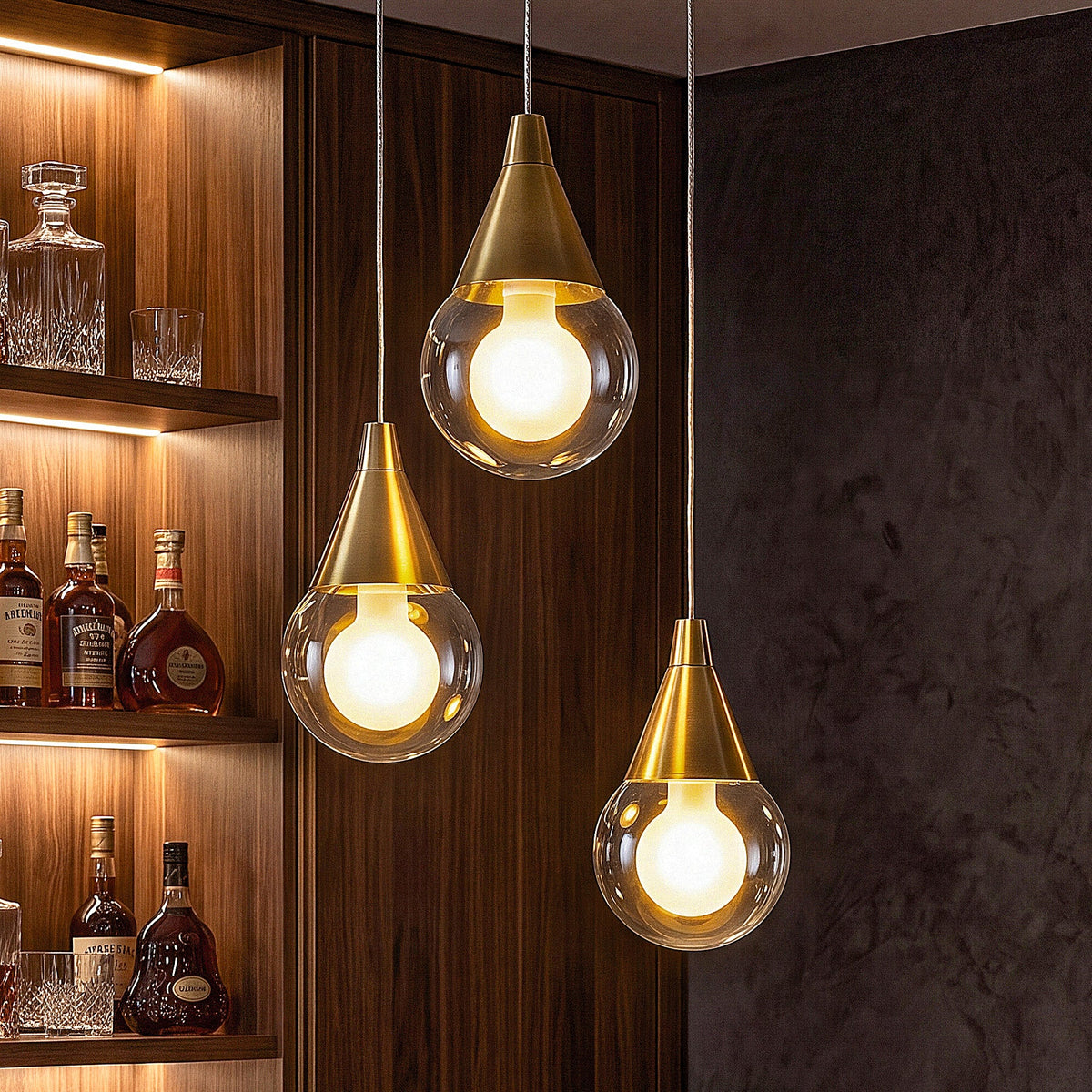 Three brushed brass glass pendant lights with integrated LED bulbs hanging in a wooden bar setting