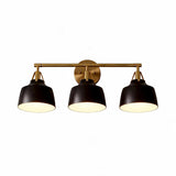 Black and gold three-light vanity light with bell-shaped shades, shown from front