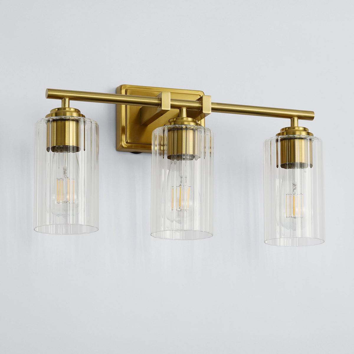 Brushed gold bathroom vanity light with three ribbed glass shades, shown from front angle