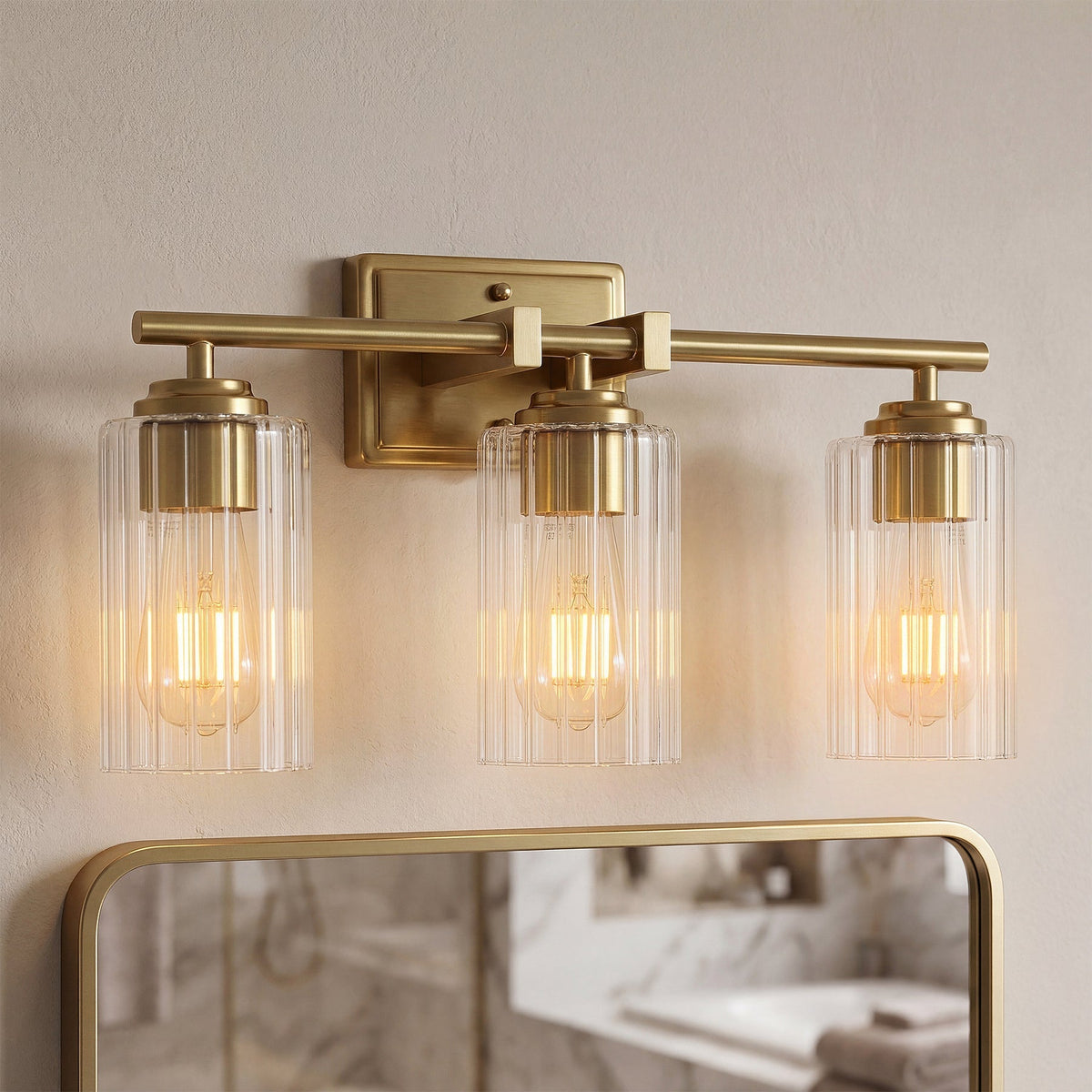 Brushed gold bathroom vanity light with three ribbed glass shades over a mirror
