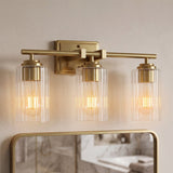 Brushed gold bathroom vanity light with three ribbed glass shades over a mirror