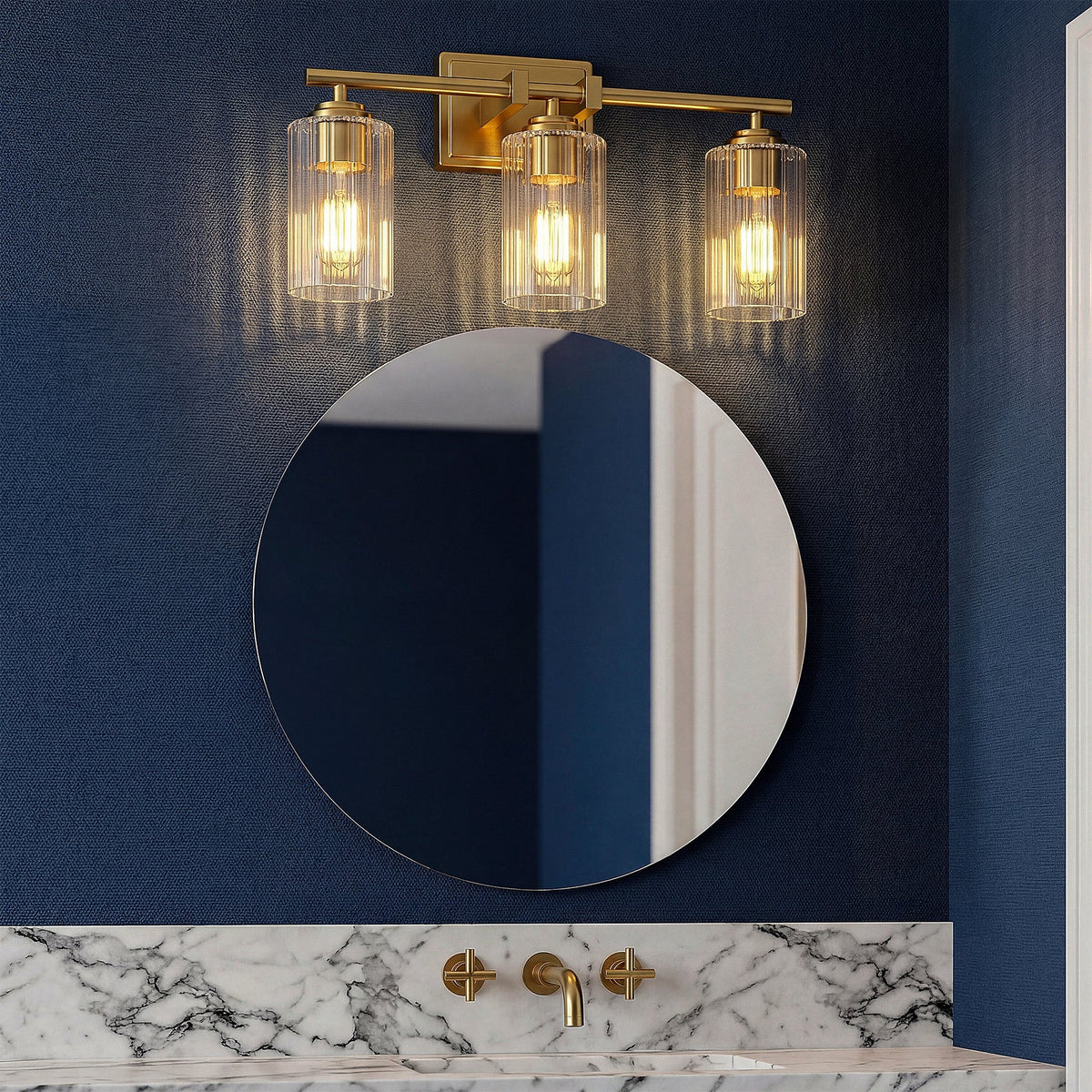 Brushed gold bathroom vanity light with three ribbed glass shades mounted above a round mirror