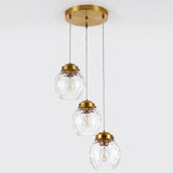 Brushed brass three-light pendant with hammered glass shades, shown from above