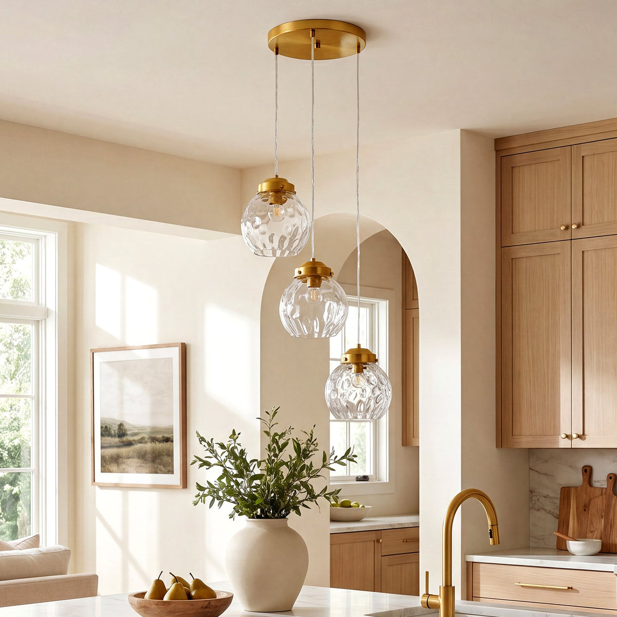 Brushed brass three-light pendant with hammered glass shades hanging in a kitchen