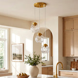 Brushed brass three-light pendant with hammered glass shades hanging in a kitchen