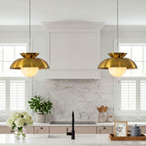 Two brass dome pendant lights with milk glass globes hang over a kitchen island