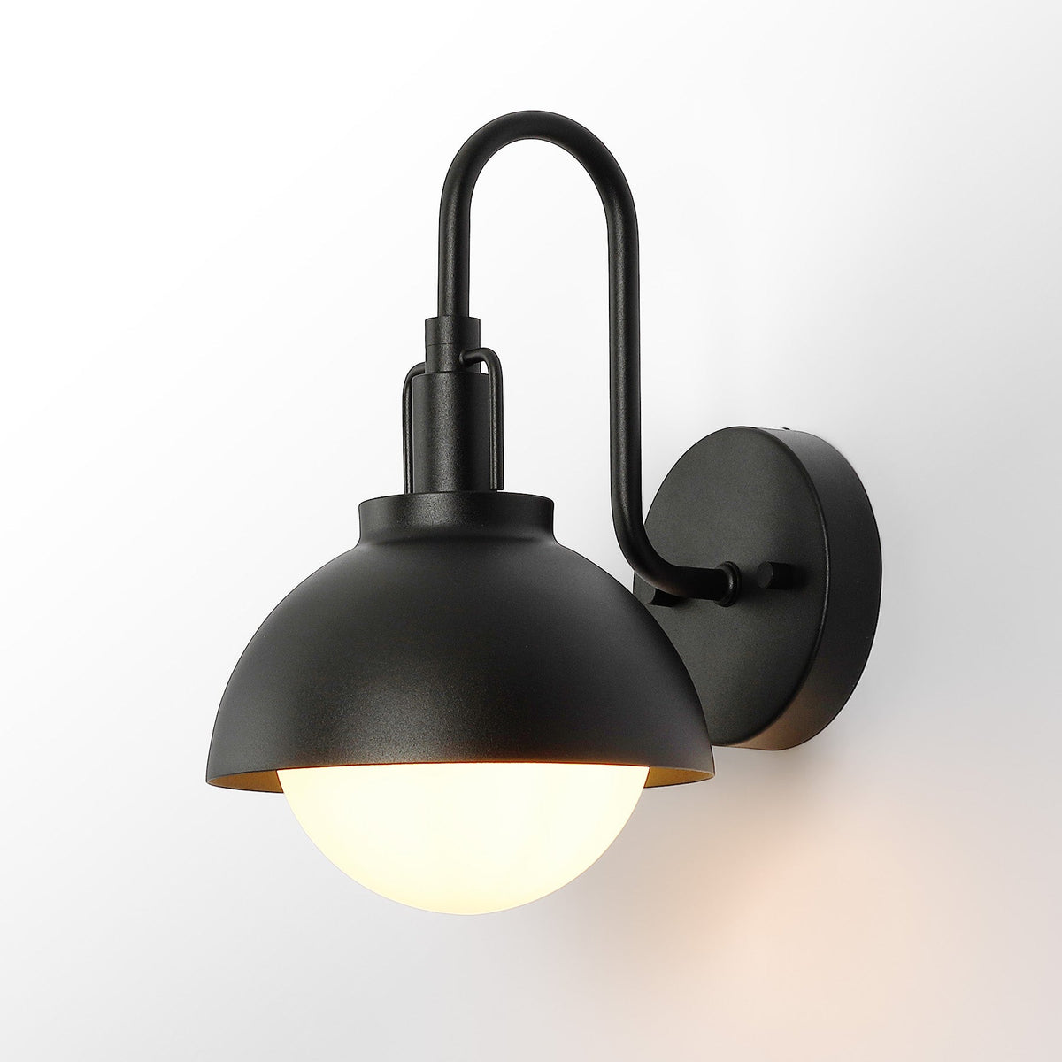 Black outdoor wall lantern with gooseneck arm and frosted glass globe, shown lit from below