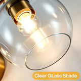 Close-up of a brushed brass bathroom vanity light with a clear glass globe shade and lit bulb