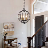 Black metal globe cage pendant light with three gold-finished bulbs, hanging in a hallway near a staircase
