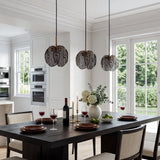 Three black pendant lights with smoky glass shades hang over a dining table