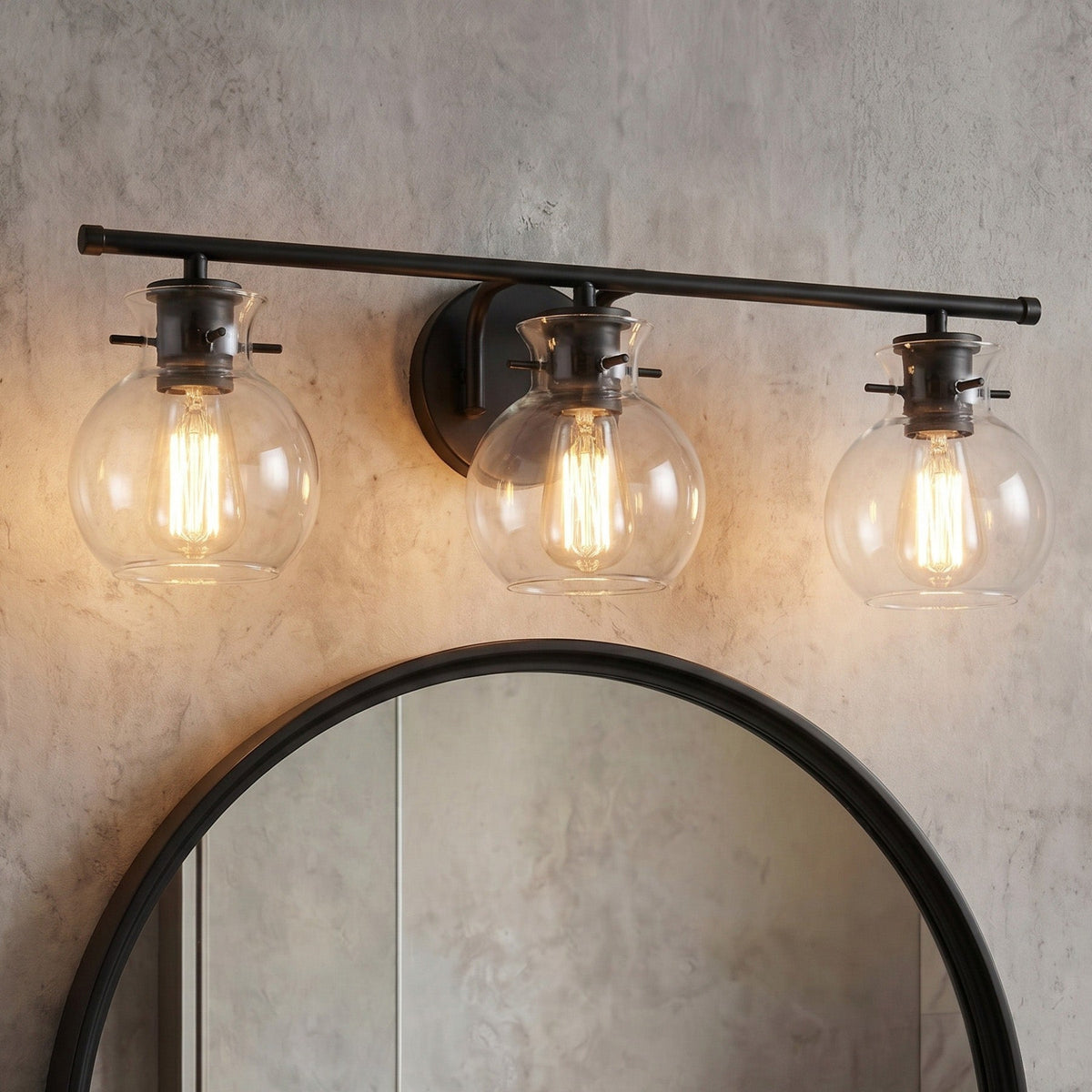 Matte black three-light vanity light with clear glass shades above a round mirror