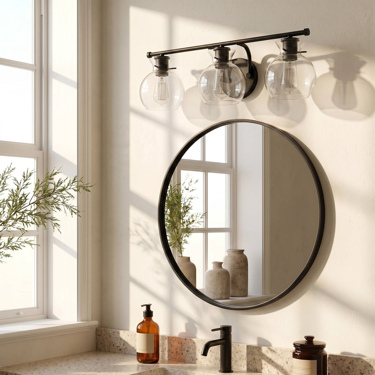 Matte black bathroom vanity light with three clear glass shades mounted above a round mirror