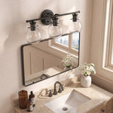 Matte black bathroom vanity light with three clear glass shades mounted above a mirror