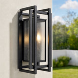 Black outdoor wall sconce with seeded glass, shown lit on a textured wall with garden view