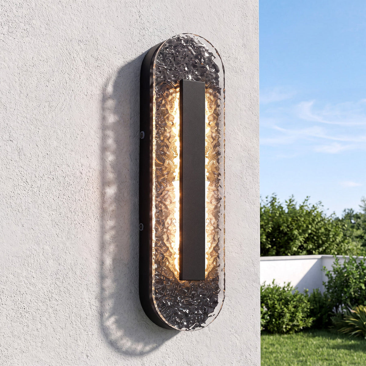 Black oval LED outdoor wall sconce with textured glass, mounted on a light-colored wall