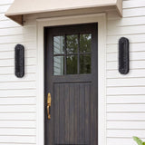 Black oval LED wall sconce with water ripple texture, mounted on white siding beside a dark front door