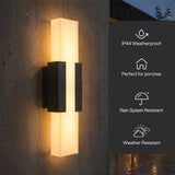 Black LED outdoor wall light with acrylic shade mounted on wet wall, glowing warmly