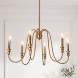 Gold six-light candle chandelier with curved arms, shown hanging in a room with white walls