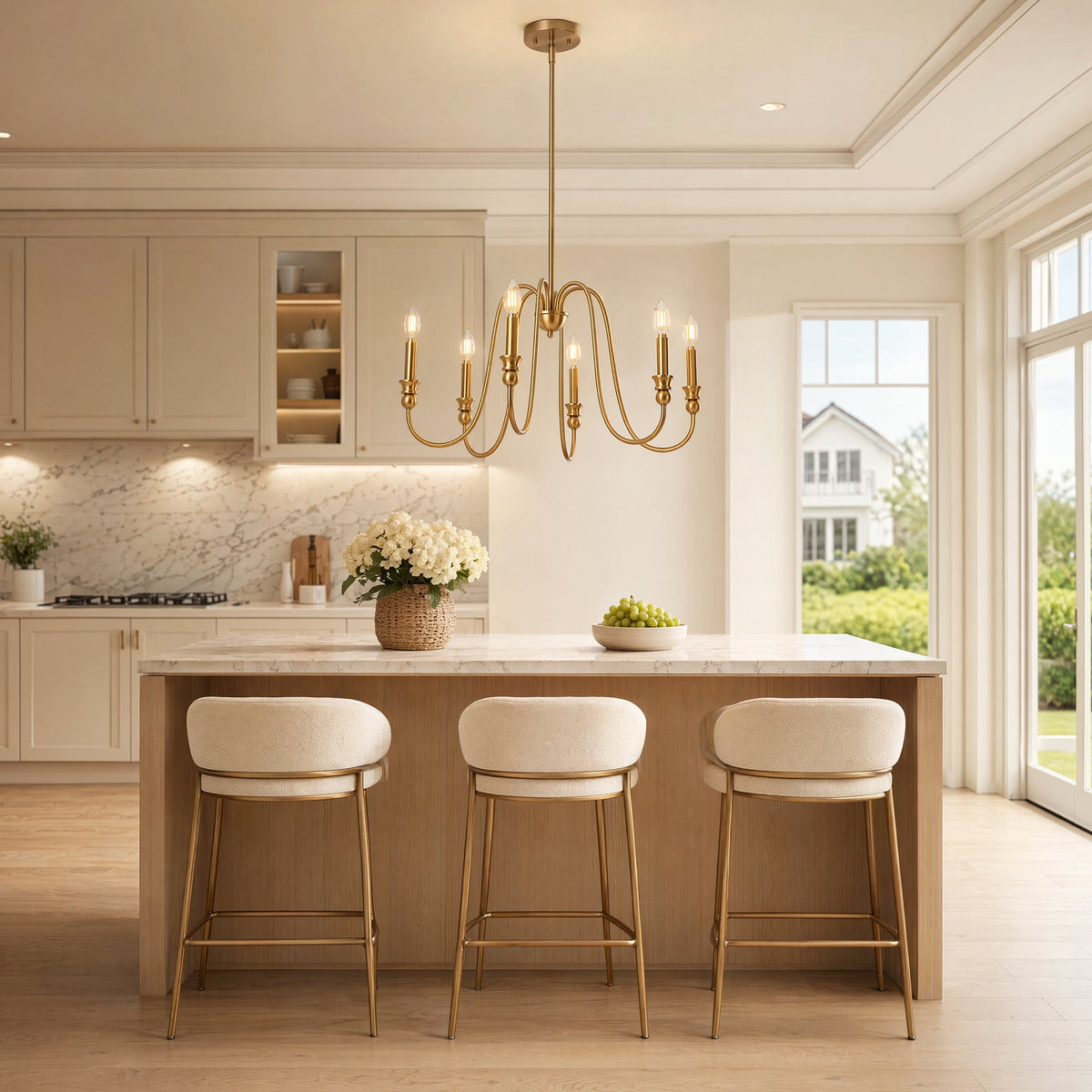 Gold six-light candle chandelier with U-shaped arms hanging above a kitchen island with bar stools