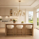 Gold six-light candle chandelier with U-shaped arms hanging above a kitchen island with bar stools