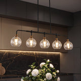 Five-light black and gold chandelier with crackle glass shades over kitchen island