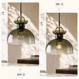 Brass pendant light with gradient green glass dome shade, shown lit in a room with natural light