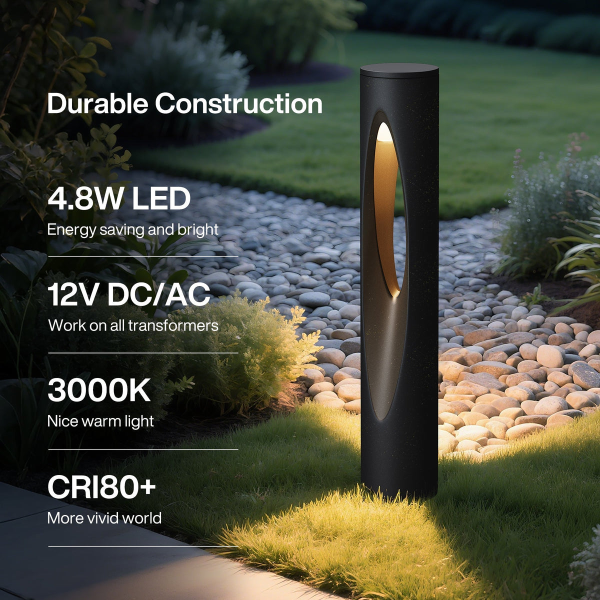Black cylindrical outdoor path light with oval cutout, emitting warm white light on grass and stone path