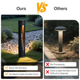 Black cylindrical LED path light with warm white glow, shown outdoors on gravel path