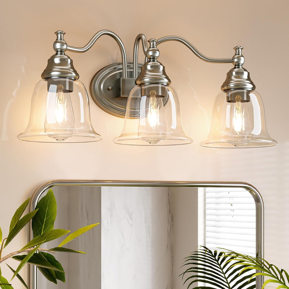 Three-light bathroom vanity light with gold finish and clear glass bell shades mounted above a mirror