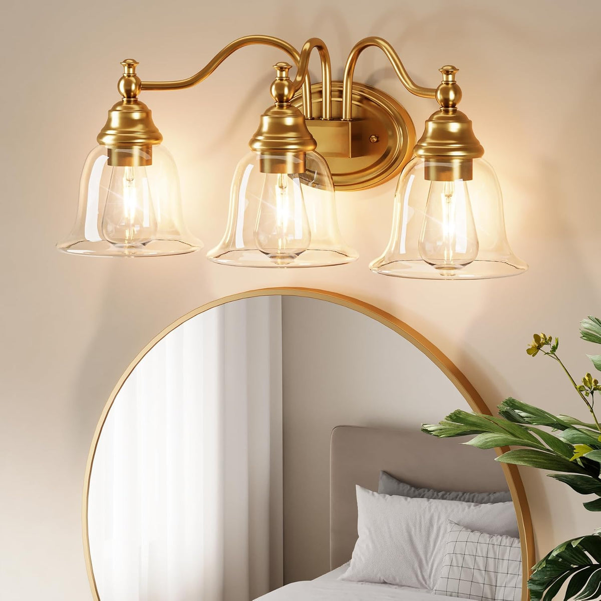 Gold bathroom vanity light with three clear glass bell shades mounted above a round mirror