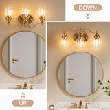 Gold bathroom vanity light with three clear glass bell shades, shown above a round mirror in a bathroom