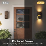 Bronze LED outdoor wall light with photocell sensor, shown on wall beside door, auto-on at night