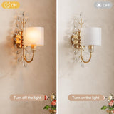 Gold crystal leaf wall sconce with fabric shade, light on, mounted on textured wall