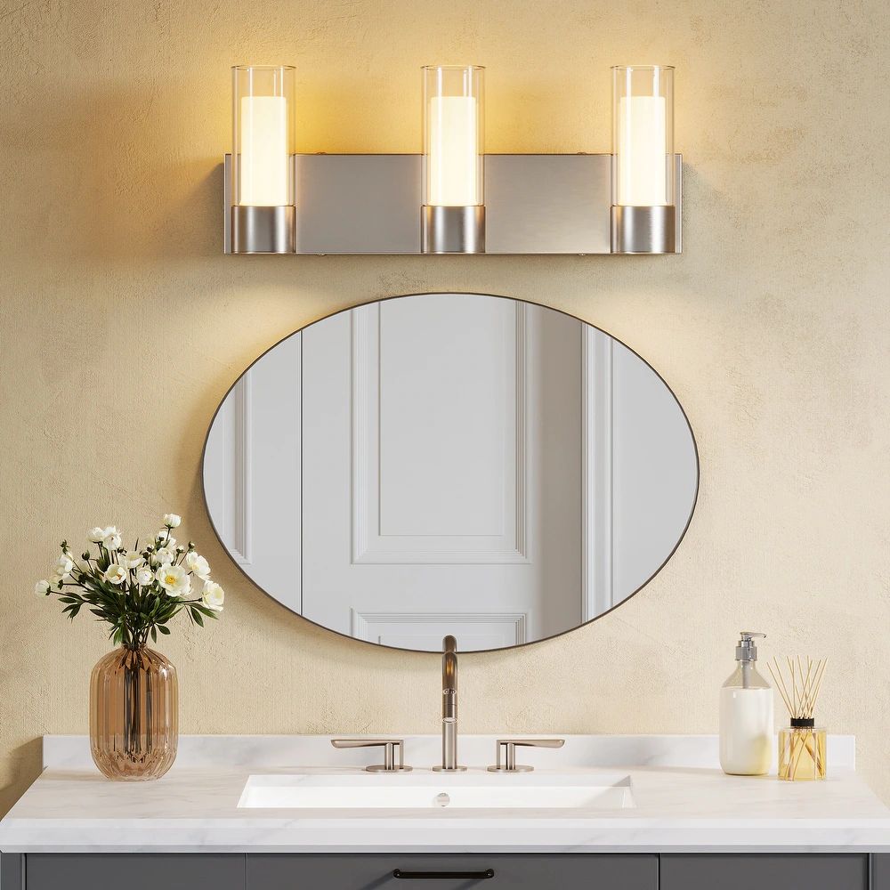 Brushed nickel three-light LED vanity light above oval mirror in bathroom