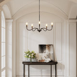Matte black five-light chandelier with adjustable arms hanging in a white arched hallway
