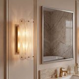 Brass wall sconce with cloud glass shades mounted on bathroom wall beside mirror