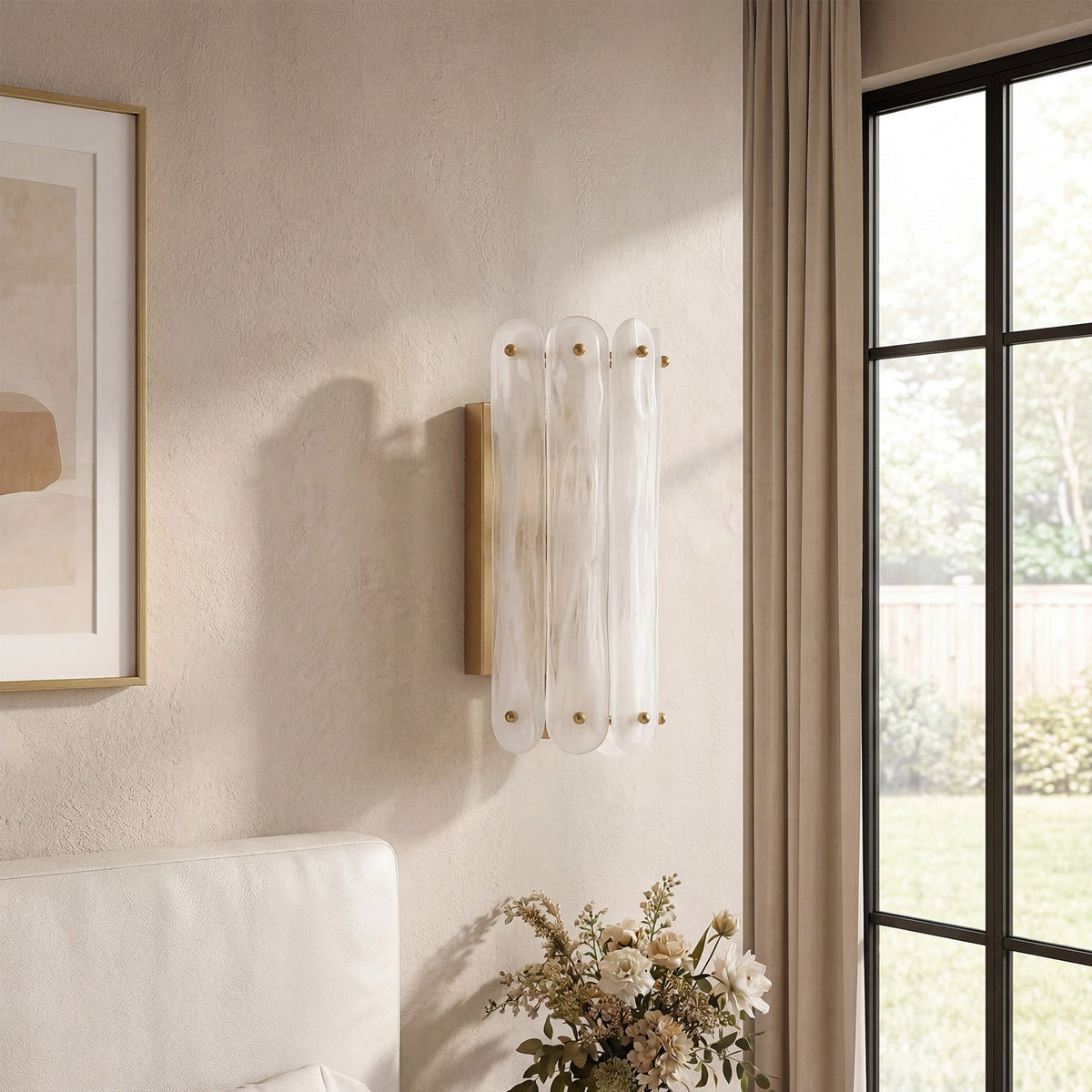 Brass wall sconce with three cloud glass shades mounted on beige wall near window