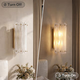 Brass wall sconce with cloud glass shades, shown lit in a bedroom setting