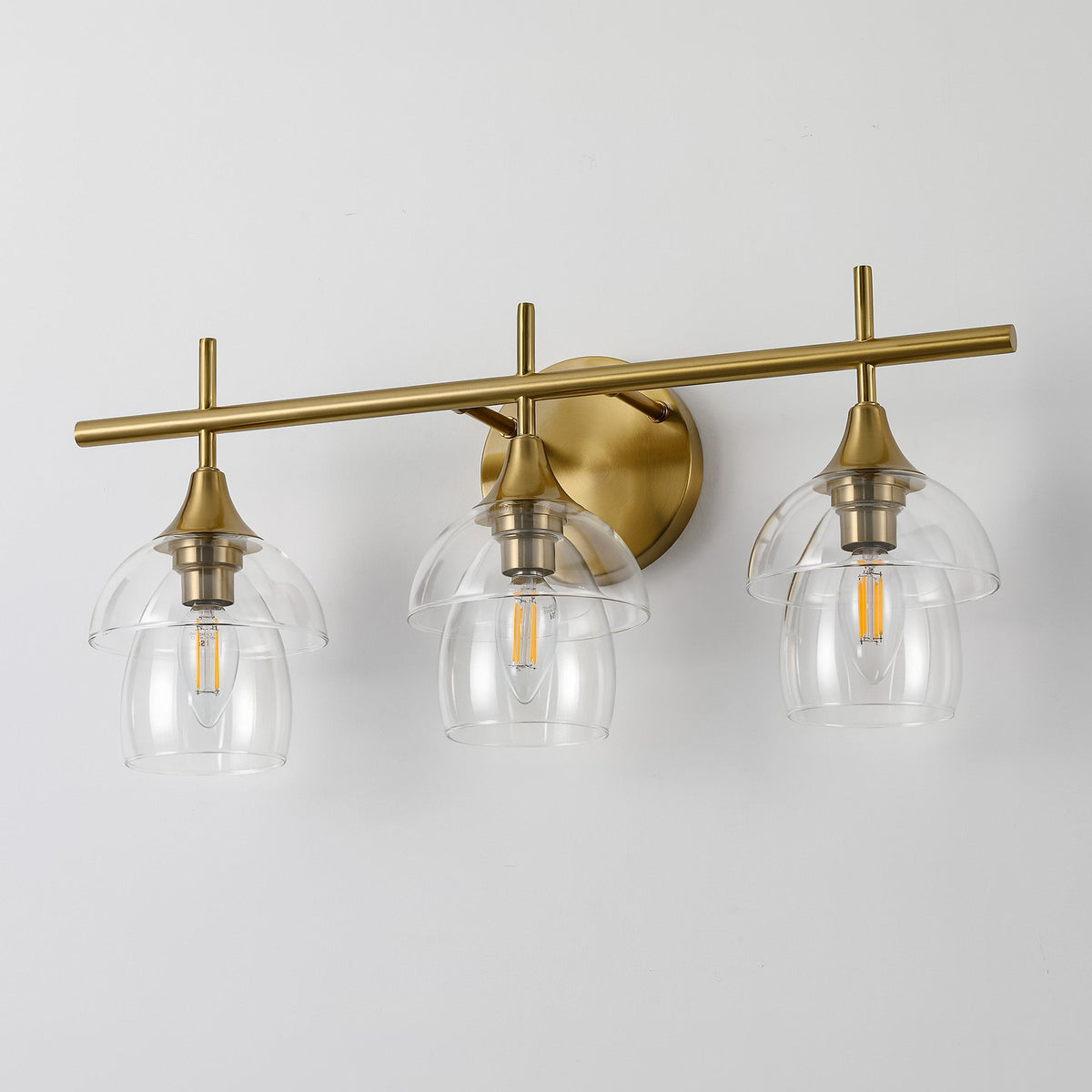 Three-light gold bathroom vanity light with clear glass shades, shown from front angle