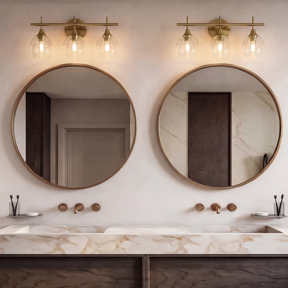Gold bathroom vanity light with three-tiered clear glass shades mounted above round mirrors
