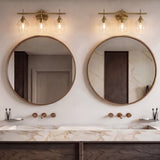 Gold bathroom vanity light with three-tiered clear glass shades mounted above round mirrors