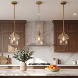 Three gold pendant lights with tiered clear glass shades hang over a kitchen island