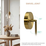 Gold pendant light with clear glass shade hanging over a wooden table near window