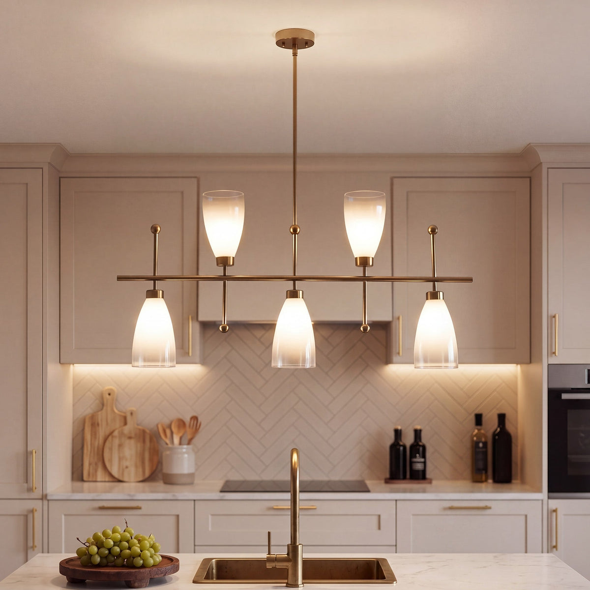 Five-light brushed brass linear chandelier with gradient frosted glass, hanging over a kitchen sink