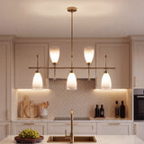 Five-light brushed brass linear chandelier with gradient frosted glass, hanging over a kitchen sink
