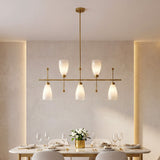 Five-light brushed brass linear chandelier with gradient frosted glass, hanging over a dining table