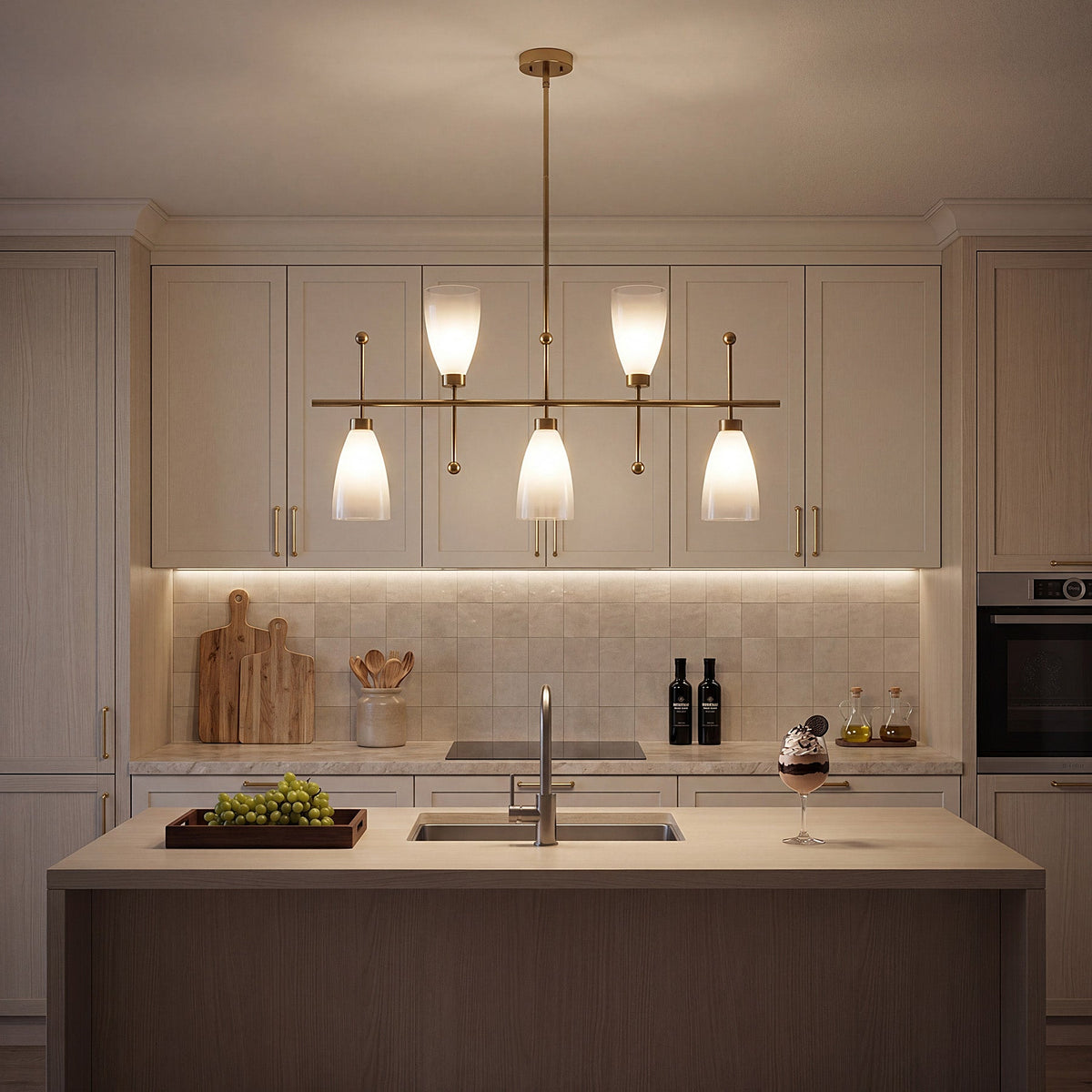 Five-light brushed brass linear chandelier with gradient frosted glass, hanging over a kitchen island