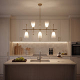 Five-light brushed brass linear chandelier with gradient frosted glass, hanging over a kitchen island
