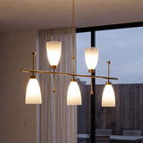 Five-light brushed brass chandelier with gradient frosted glass shades, hanging in a room with large window